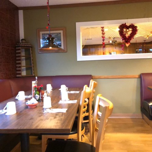 Cozy restaurant interior with a wooden table set for dining, decorated with heart-shaped ornaments and warm lighting.