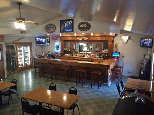 A cozy bar interior with a wooden counter, stools, tables, and a few TVs, featuring a relaxed atmosphere.
