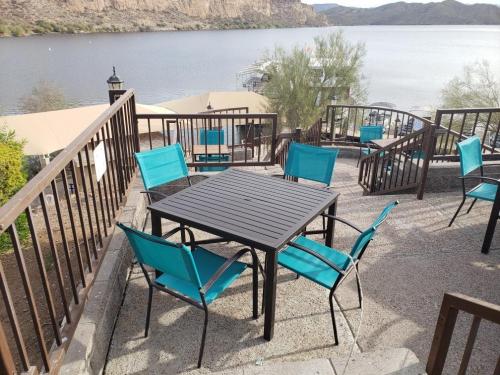 A patio with a black table and turquoise chairs overlooking a lake and mountains in the background.