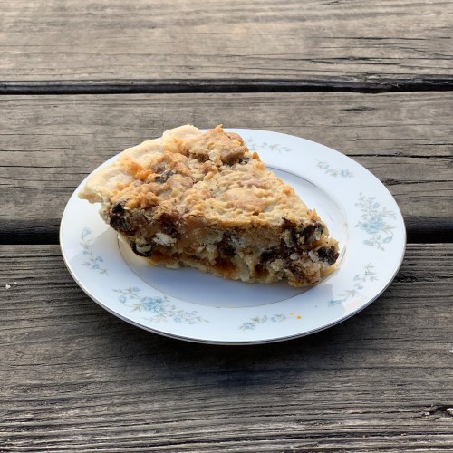 A slice of pie on a floral-patterned plate, resting on a wooden surface.