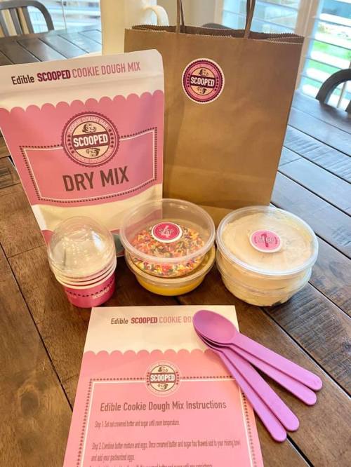 A package of edible cookie dough mix with sprinkles, instructions, and utensils on a wooden table.