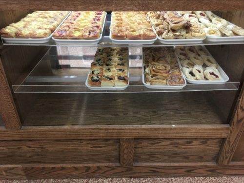 A display case filled with various pastries, including sweet rolls, cinnamon rolls, and fruit-topped desserts.