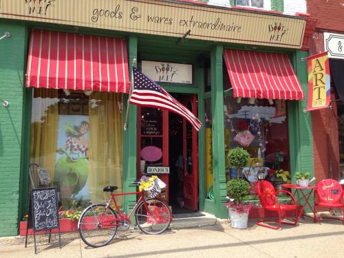 A colorful storefront with red and white striped awnings, an American flag, and a bicycle outside.