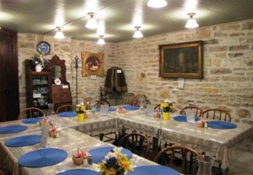 Cozy dining room with stone walls, wooden chairs, and tables set with blue plates and flower centerpieces.
