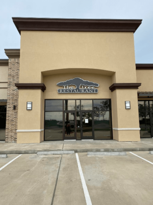 Exterior view of "The Tree Restaurant" with a large entrance and signage, set in a commercial building.