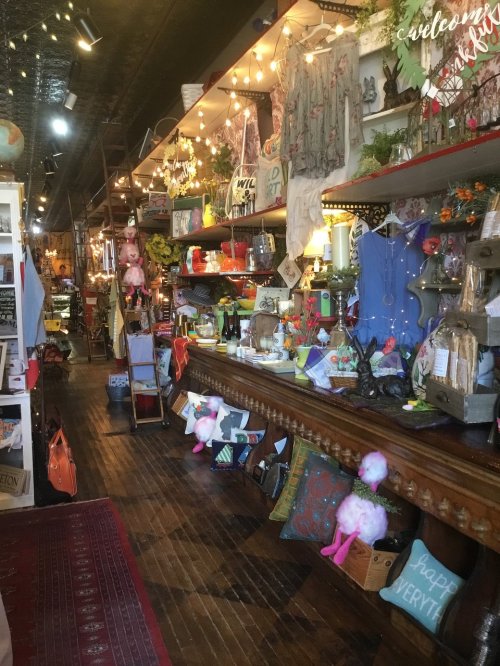 A cozy shop interior filled with colorful decor, vintage items, and whimsical decorations along wooden shelves.