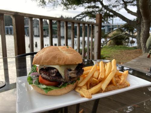 A juicy burger with lettuce, tomato, and cheese, served with golden fries, by a scenic riverside view.