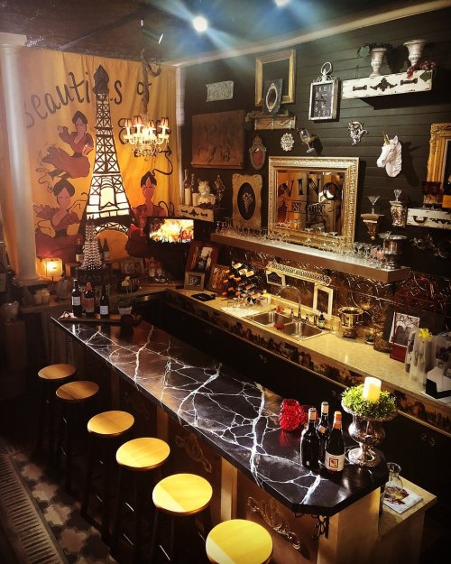 A stylish home bar with a marble countertop, vintage decor, and an Eiffel Tower-themed backdrop. Cozy and inviting atmosphere.