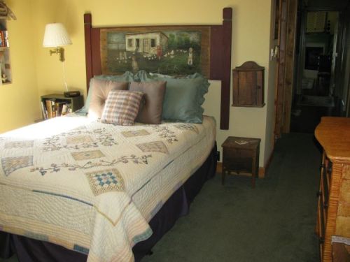 Cozy bedroom with a quilted bed, decorative pillows, a wooden nightstand, and a warm color scheme.