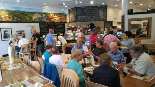 A busy café with patrons dining and chatting, while staff serve food in a warm, inviting atmosphere.