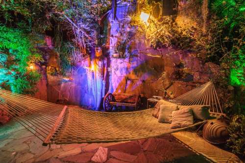 A cozy hammock surrounded by vibrant greenery and colorful lights, creating a relaxing outdoor atmosphere.