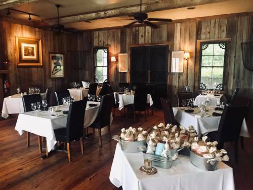 Elegant restaurant interior with wooden walls, tables set with white linens, and a display of desserts in a silver bowl.