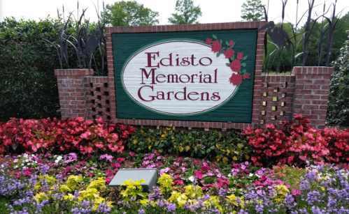 Sign for Edisto Memorial Gardens surrounded by colorful flowers and greenery.