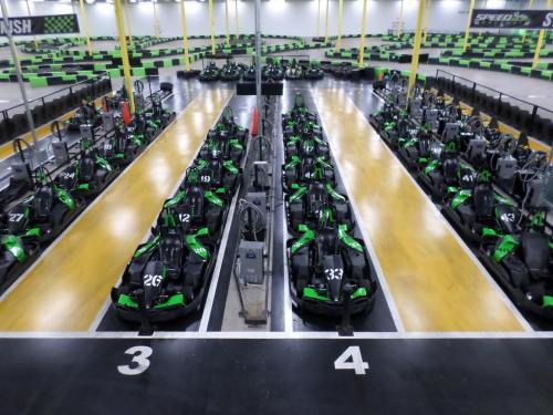 A view of a go-kart track with multiple green and black go-karts lined up in designated spaces.