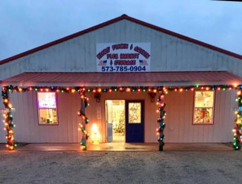 A festive market building decorated with colorful lights, featuring a sign that reads "Pigeon & Coon Flea Market."
