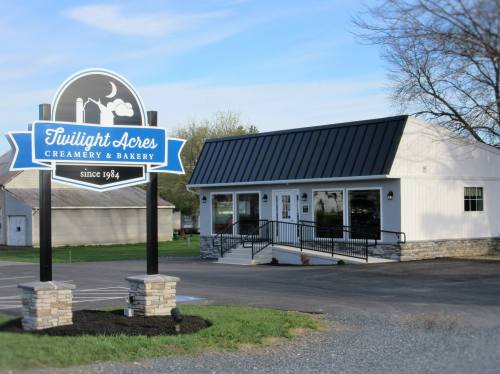 A white building with a black roof, featuring a sign for "Twilight Acres Creamery & Bakery" since 1984.