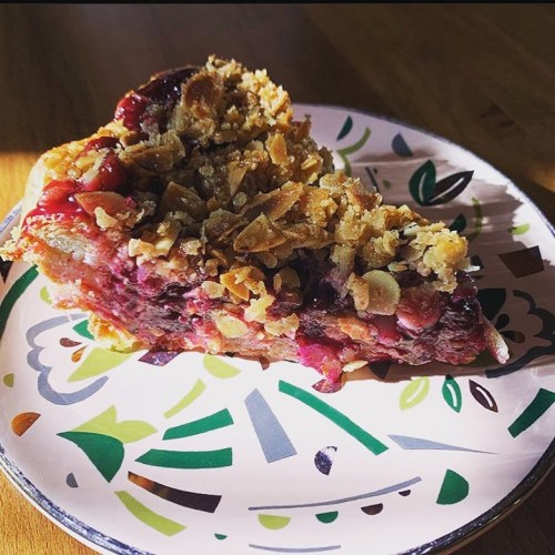 A slice of pie topped with a crunchy oat crumble, served on a decorative plate with colorful patterns.