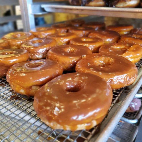 A tray of freshly glazed donuts, showcasing a shiny caramel-colored icing.