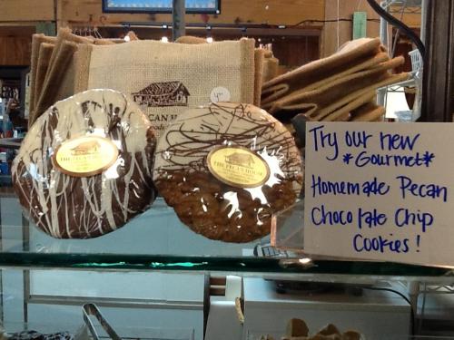 Two large cookies displayed in a glass case, one drizzled with white chocolate and the other with dark chocolate.
