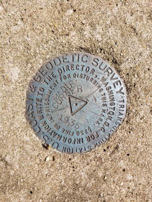A metal survey marker embedded in concrete, inscribed with "Coast & Geodetic Survey" and dated 1935.