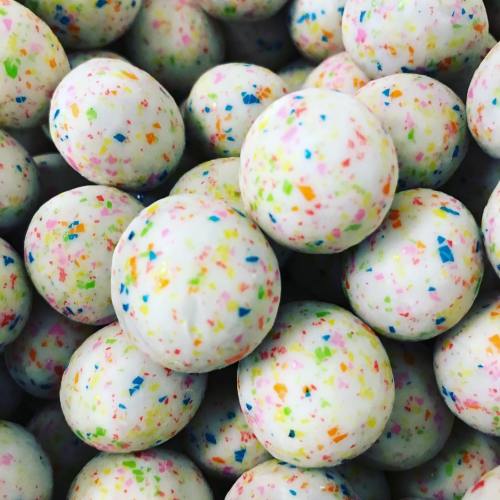 A close-up of colorful, speckled white balls stacked together, resembling candy or decorative items.