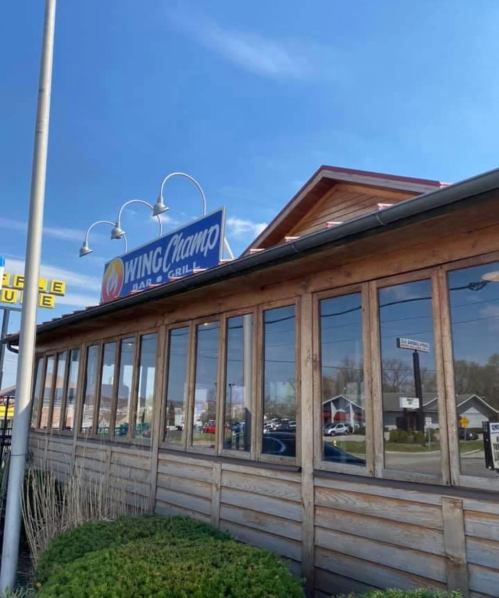 Exterior of Wing Champ Bar & Grill, featuring large windows and a blue sky in the background.