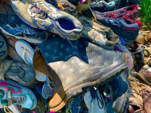 A chaotic pile of various shoes, including sneakers, sandals, and boots, in a disorganized heap.
