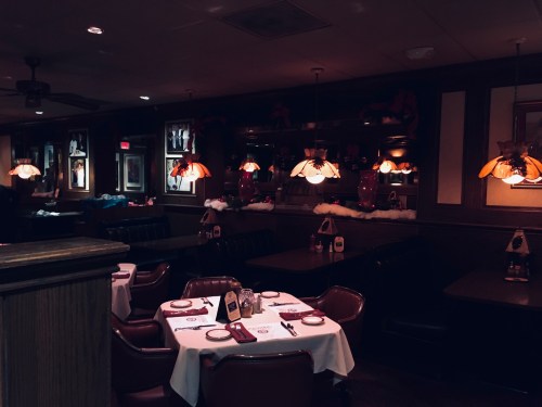 Cozy restaurant interior with dim lighting, tables set for dining, and festive decorations on the walls.