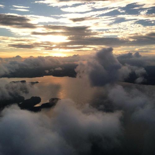 Aerial view of a serene landscape with clouds and a sunset reflecting on a calm body of water.