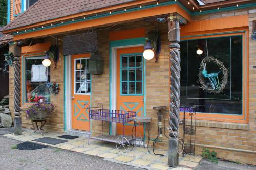 A charming brick storefront with orange doors, decorative windows, and unique outdoor decor.