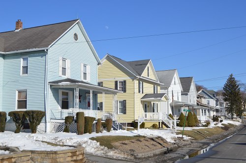 Row of colorful houses with snow on the ground, under a clear blue sky.