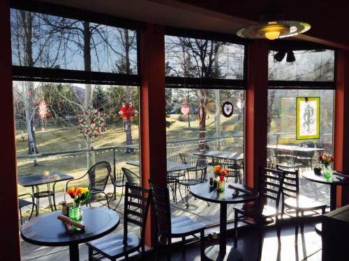 Cozy café interior with tables, colorful flowers, and large windows showcasing a sunny outdoor view.