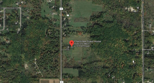 Aerial view of Chanticleer Guest House, surrounded by greenery and fields, with nearby roads visible.