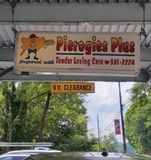 Sign for "Pierogies Plus" featuring a cartoon pierogi character, with a clearance sign below reading "9 ft. CLEARANCE."
