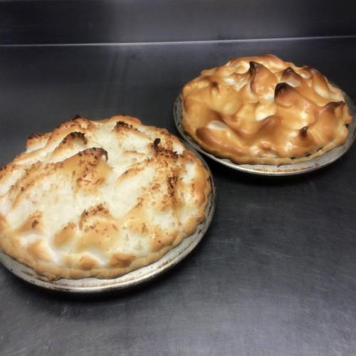 Two freshly baked pies with golden-brown meringue topping, one lightly toasted and the other more caramelized.