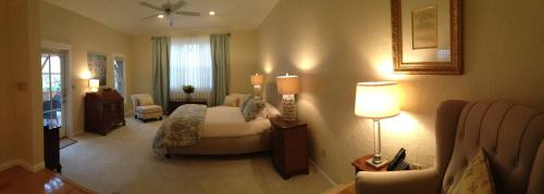 Cozy bedroom with a large bed, soft lighting, and a seating area, featuring light-colored walls and decorative accents.