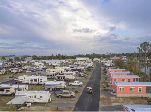 Aerial view of a large RV park with numerous trailers and colorful cabins under a cloudy sky.