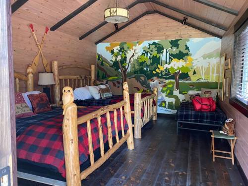 Cozy cabin interior with wooden beds, plaid bedding, and a colorful nature mural on the wall.