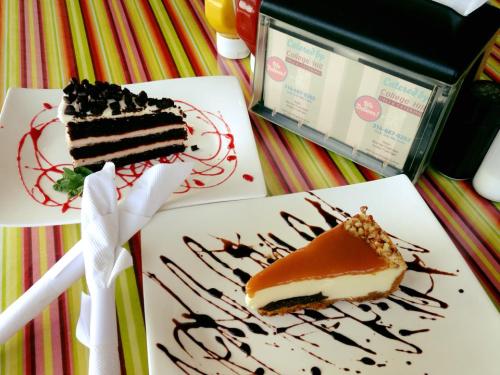 A slice of chocolate cake and a caramel cheesecake on a colorful striped table, garnished with sauces.