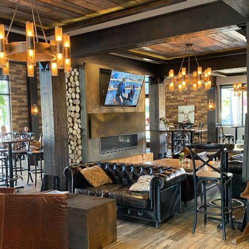 Cozy restaurant interior with wooden decor, a fireplace, and a large TV, featuring dim lighting and comfortable seating.