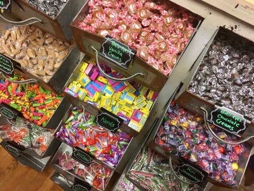 Colorful candy bins filled with various sweets, including vanilla creams, chocolate creams, and assorted candies.