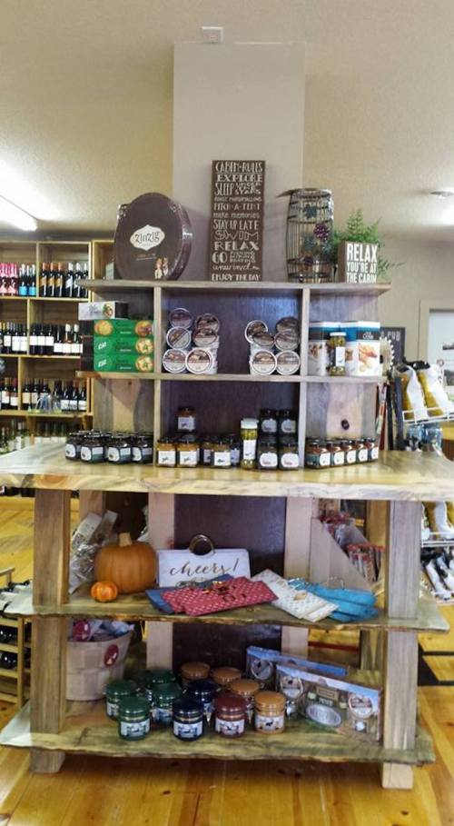 A wooden display shelf filled with jars, candles, and decorative items in a cozy store setting.