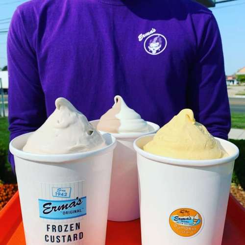 Three cups of frozen custard in different flavors, held by a person wearing a purple Erna's shirt.