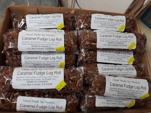 A box filled with packages of Caramel Fudge Log Rolls, labeled with ingredients and pricing.