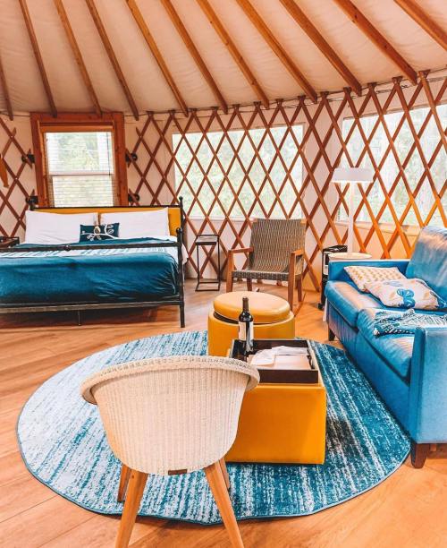 Cozy yurt interior featuring a bed, seating area, round rug, and a bottle of wine on a table. Bright and inviting atmosphere.