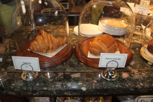 A croissant and a pain au chocolat displayed under glass domes on a marble countertop.