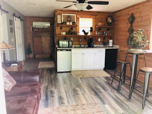 Cozy kitchen and living area with wooden walls, modern appliances, and a small dining table.