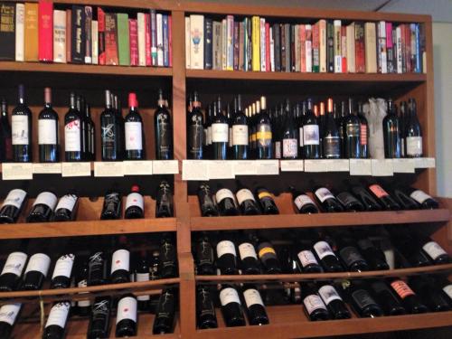A wooden shelf displaying various wine bottles and a collection of books above them.