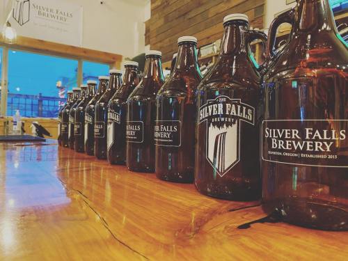 A row of brown glass growlers from Silver Falls Brewery lined up on a wooden bar.