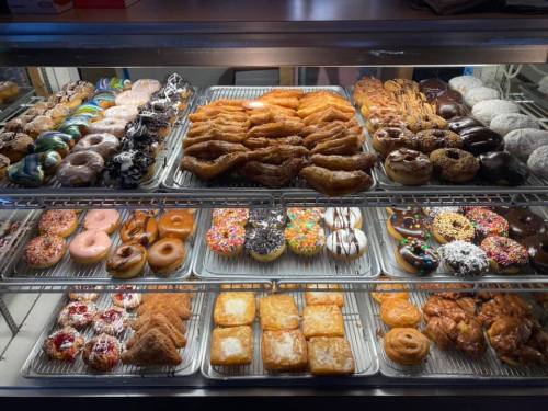 A display case filled with a variety of colorful donuts, pastries, and sweet treats.
